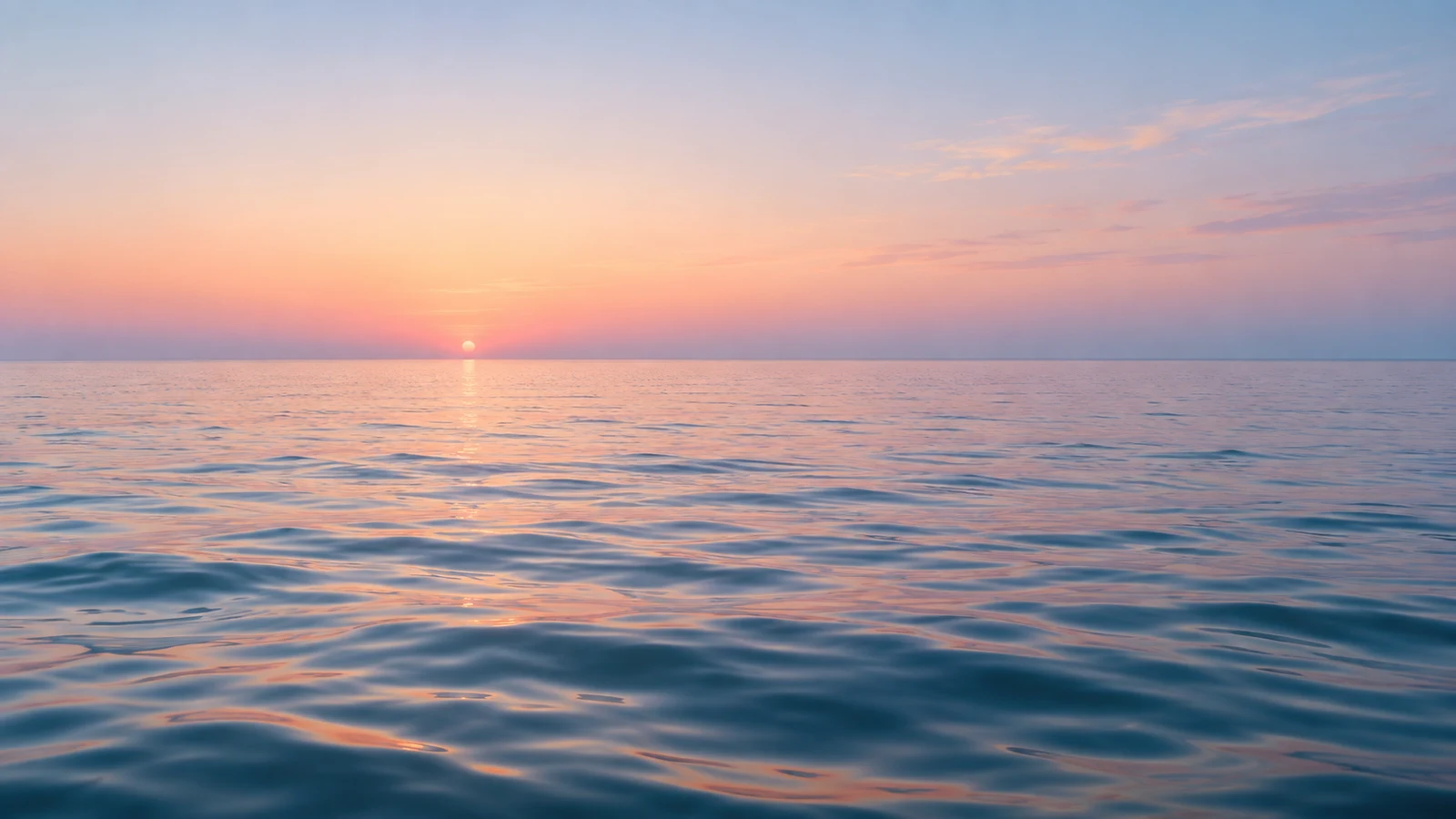 Mar calmo ao amanhecer, com o sol no horizonte e o céu em tons de rosa e azul refletidos na água